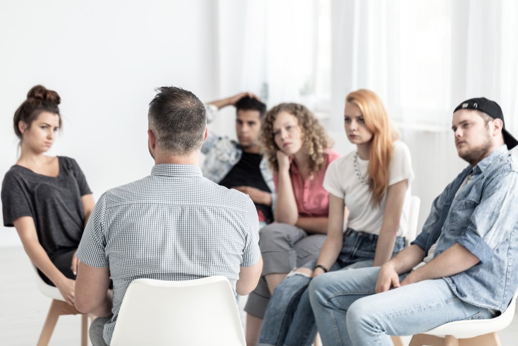 A group of people sitting in a circle with an addiction therapist.