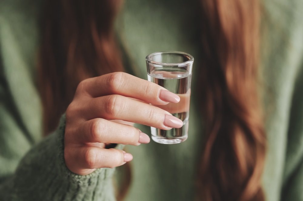 Woman holding a shot of vodka wondering if vodka is addictive