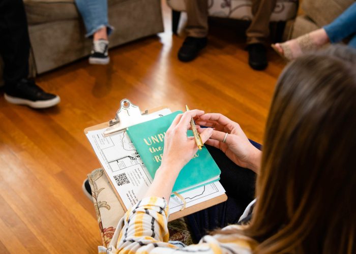 A therapist holding a gold pen while surrounded by group of people.